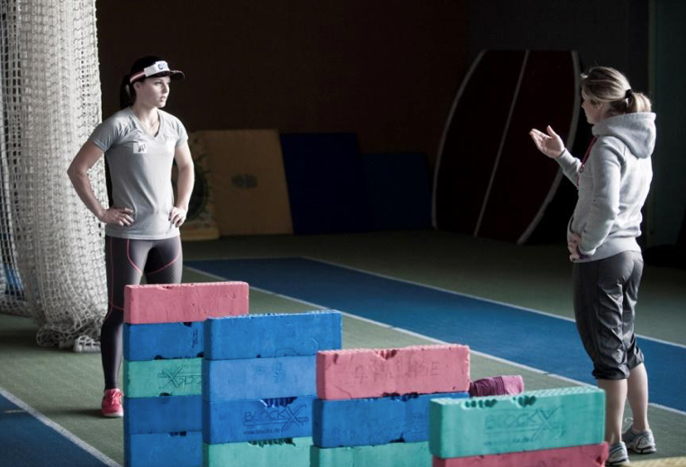 Two people face off in an indoor gym beside stacked foam blocks.