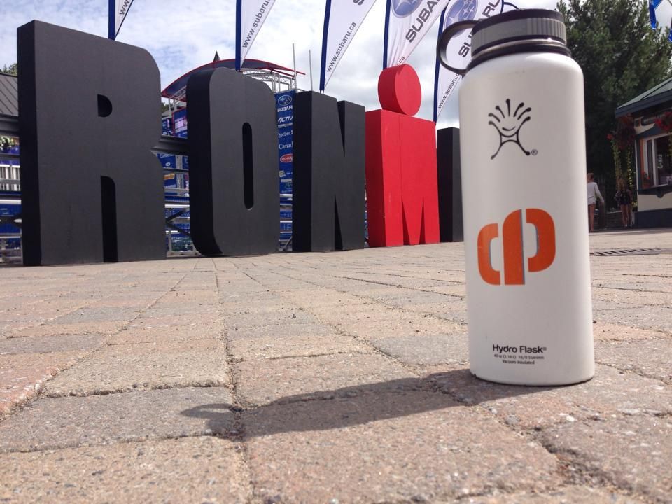 White water bottle in foreground on pavement, with large black, gray, and red “HUMN” letters behind it.