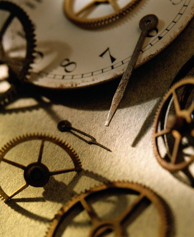 Close-up of antique clock gears and watch hands on a sepia-toned clock face.