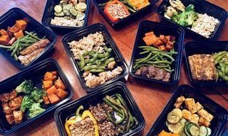 Assorted meal prep containers with vegetables, rice, and protein arranged on a table