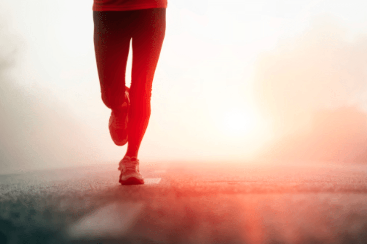 Runner in red pants jogging on a misty road at sunrise