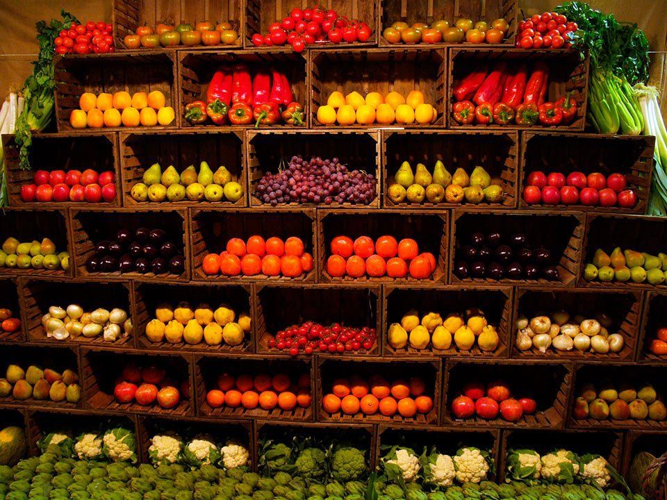 Colorful fruit and vegetable display stacked in wooden crates at a market stall