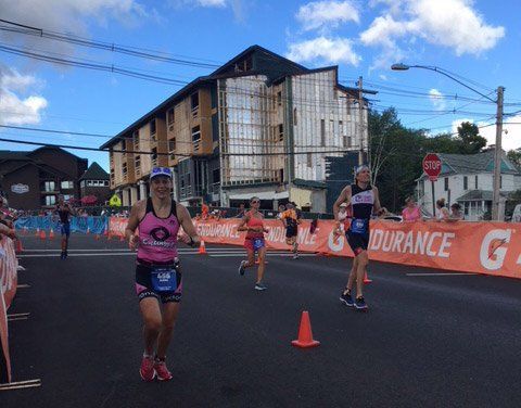 Marathon runners on a city street near orange cones and barriers, with a damaged building in the background
