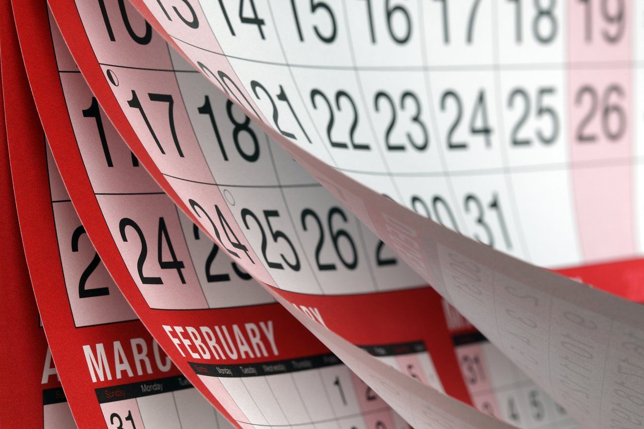 Close-up of a red wall calendar with pages flipping to February dates