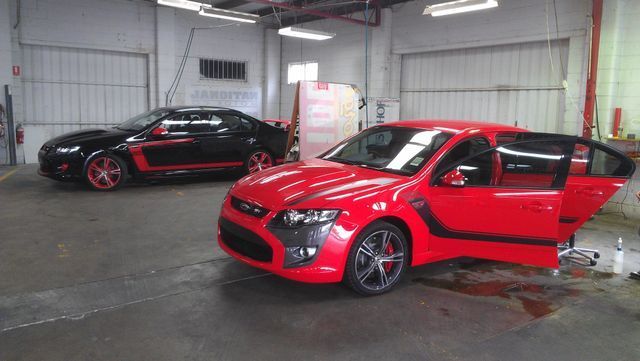 A Red Car Is Parked Next To A Black Car In A Garage – Adelaide, SA - Sola Bloc Window Tinting