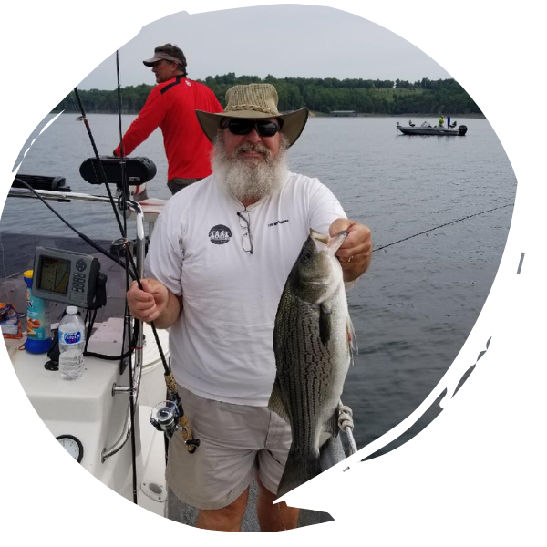 Angler on a boat holding a large striped fish, with another person fishing in the background.