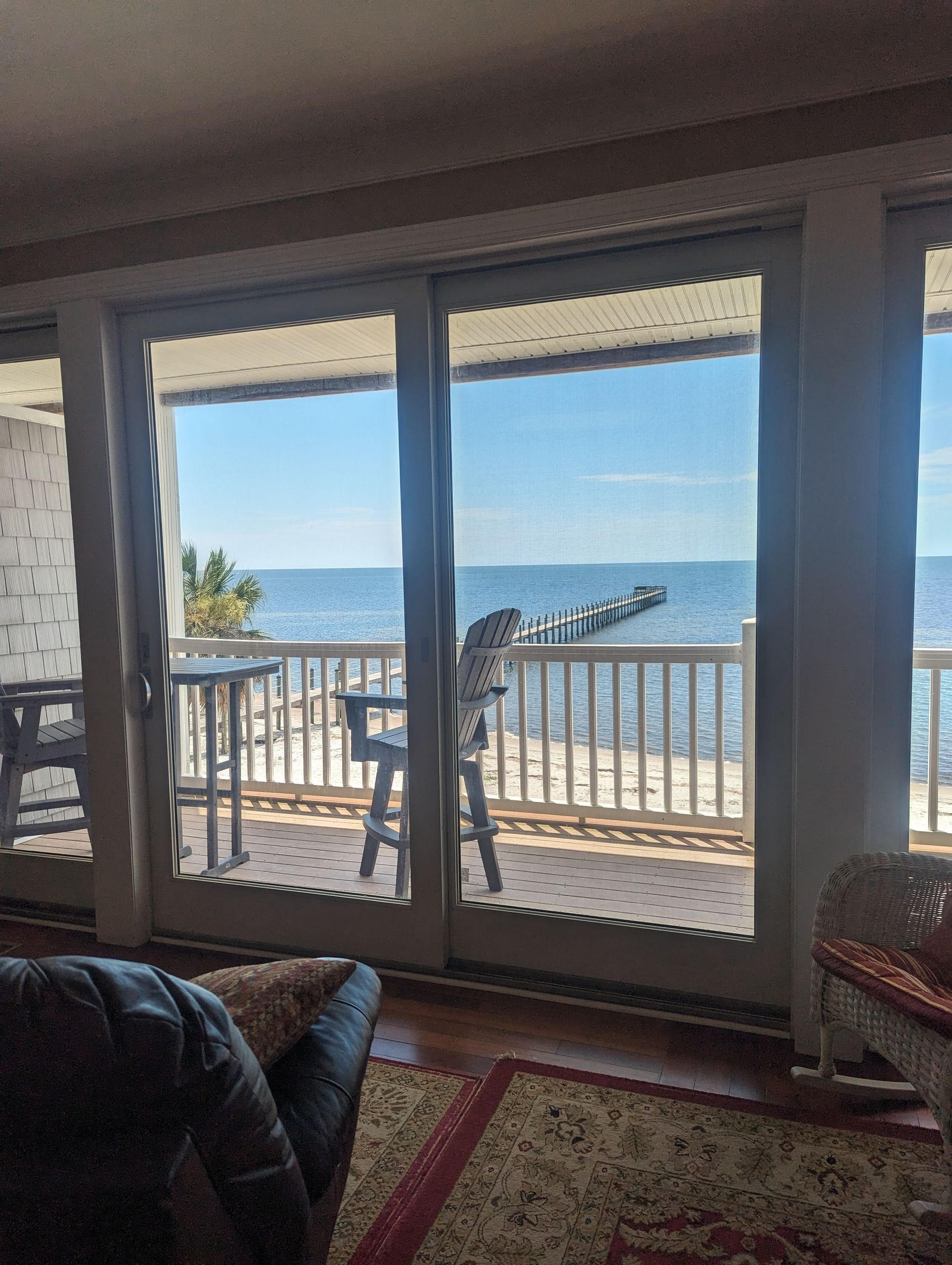 Sliding glass doors open to a waterfront view. A wooden deck and pier extend over the water.