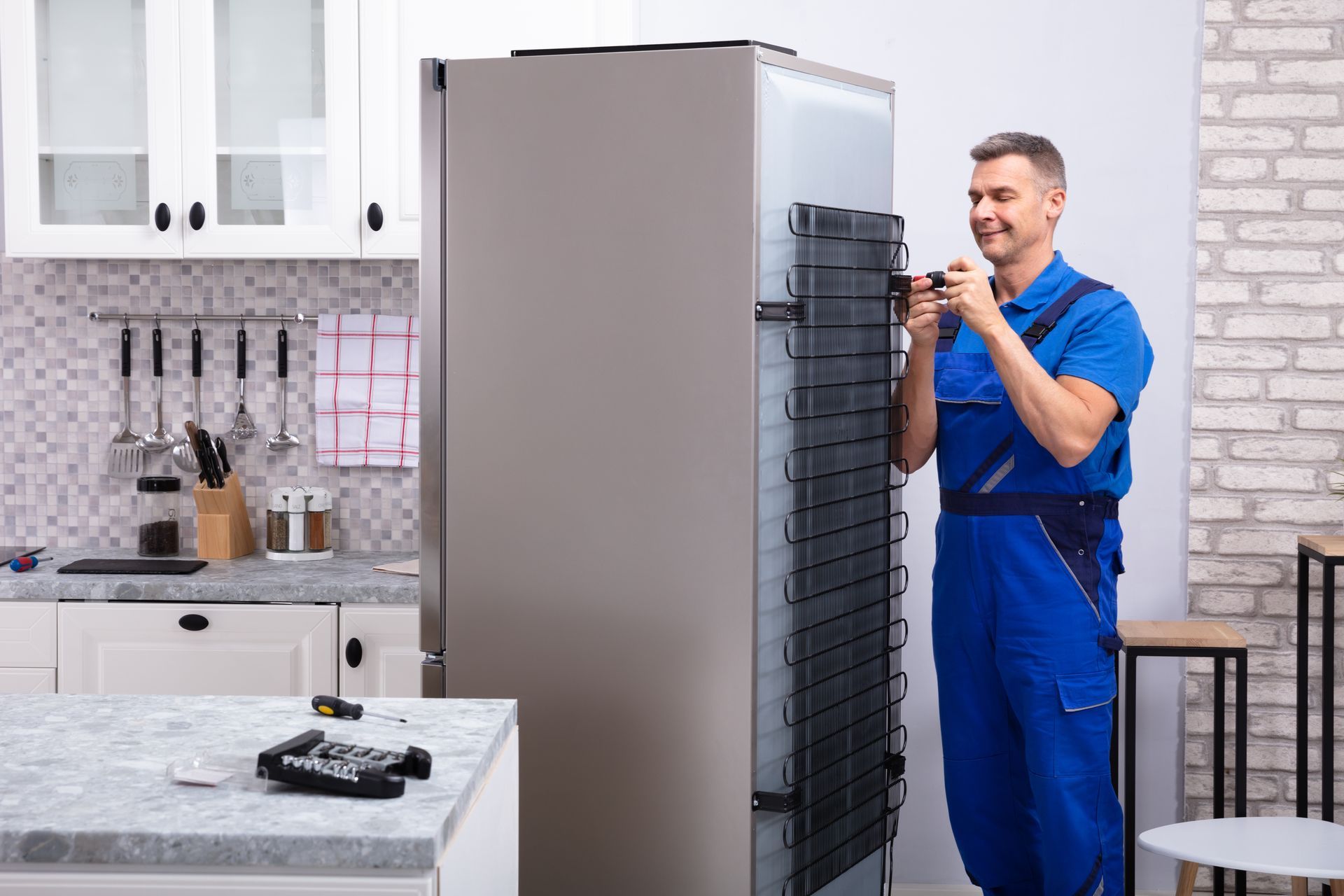A man is fixing a refrigerator in a kitchen.