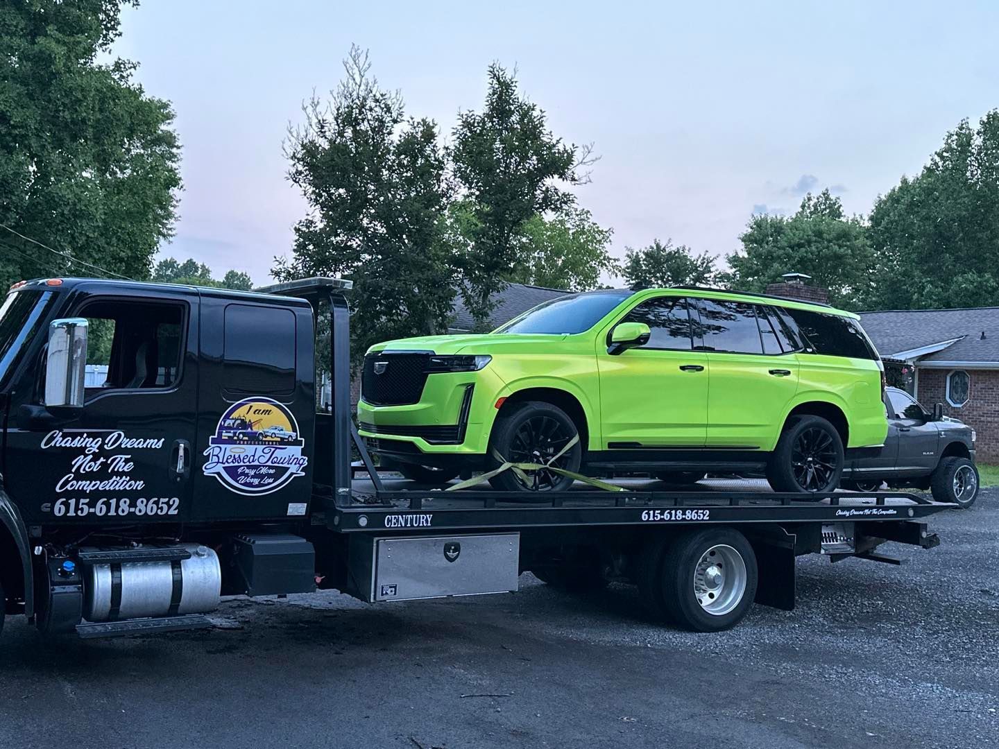 Lime green Cadillac SUV loaded on a black tow truck.