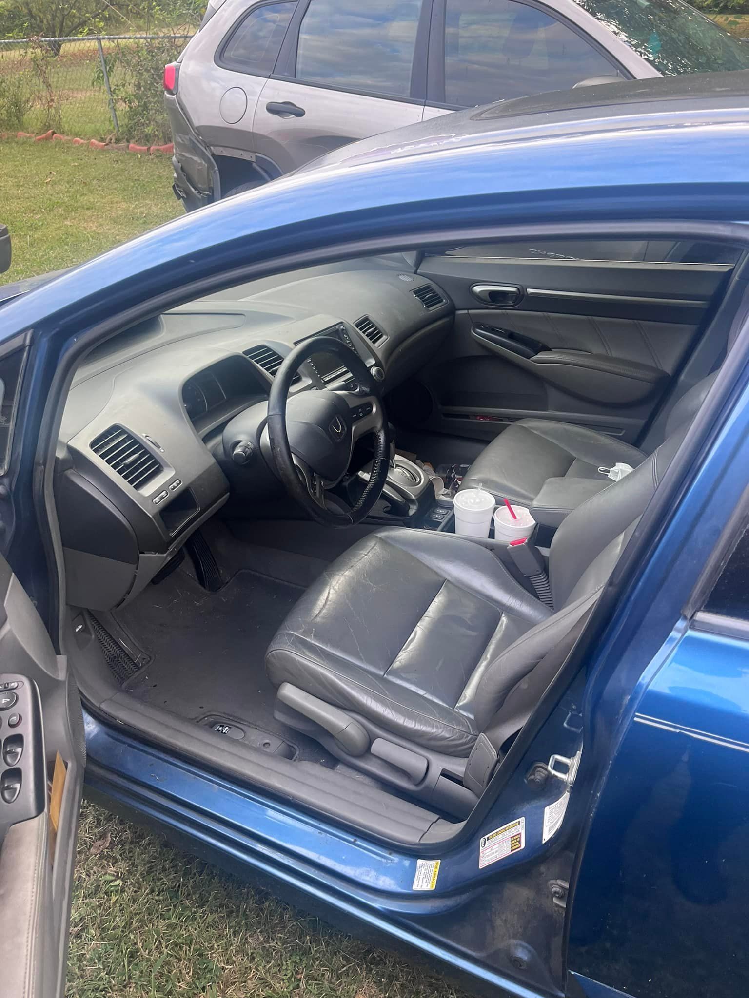Blue Honda Civic interior with black seats, steering wheel, and dashboard. Door open.