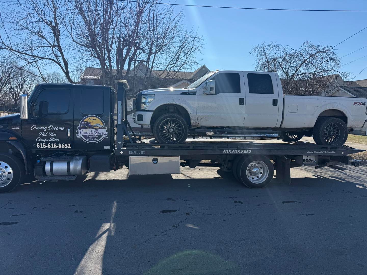 Tow truck carrying a white pickup truck on a city street.
