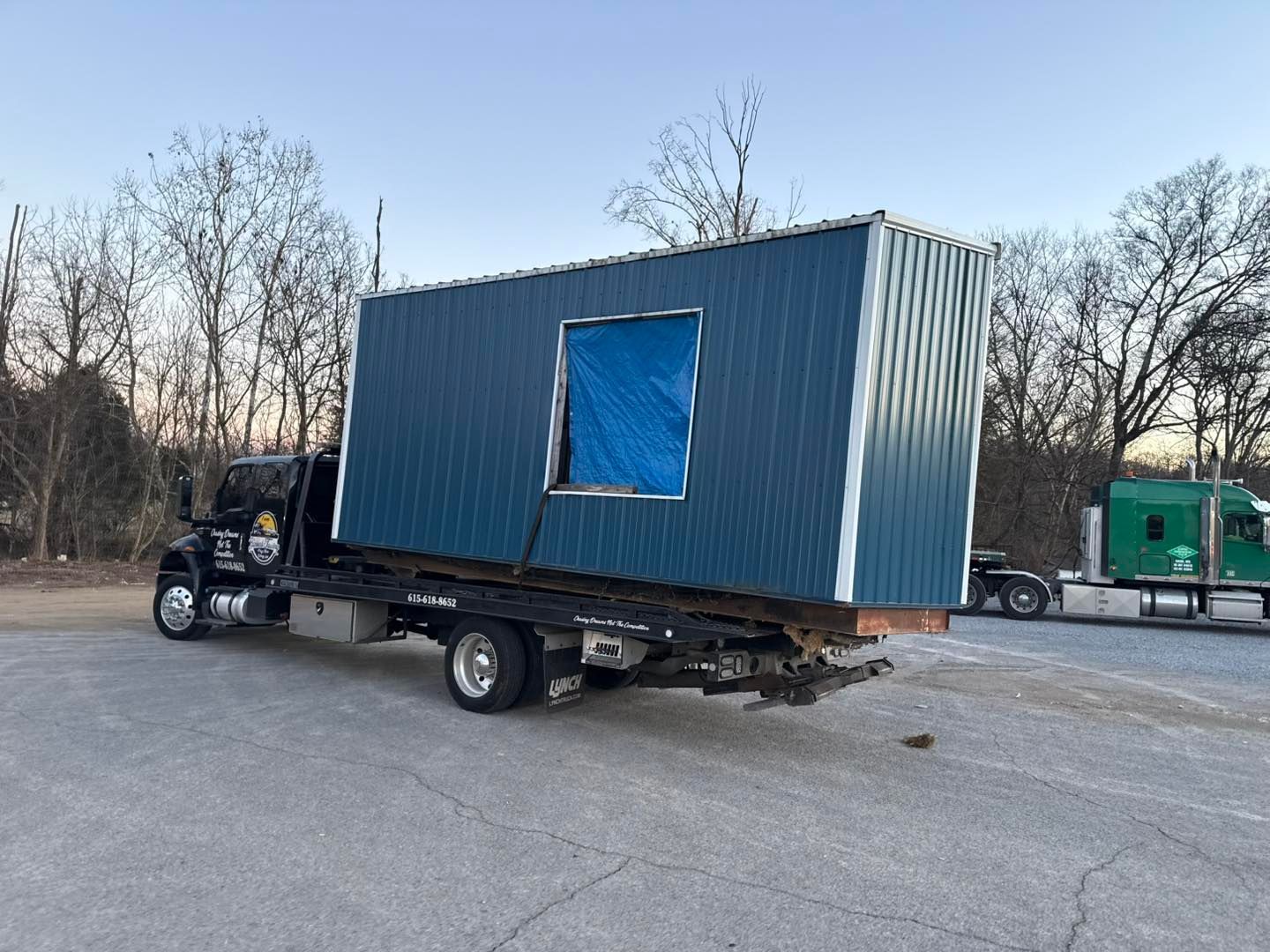 A blue metal structure on a flatbed truck in a parking lot.
