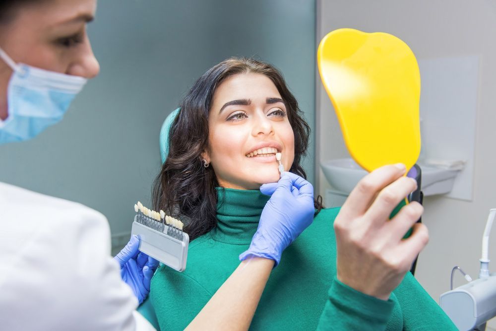 A Woman Is Sitting In A Dental Chair Looking At Her Teeth In A Mirror — Port Denture Clinic In Kempsey, NSW