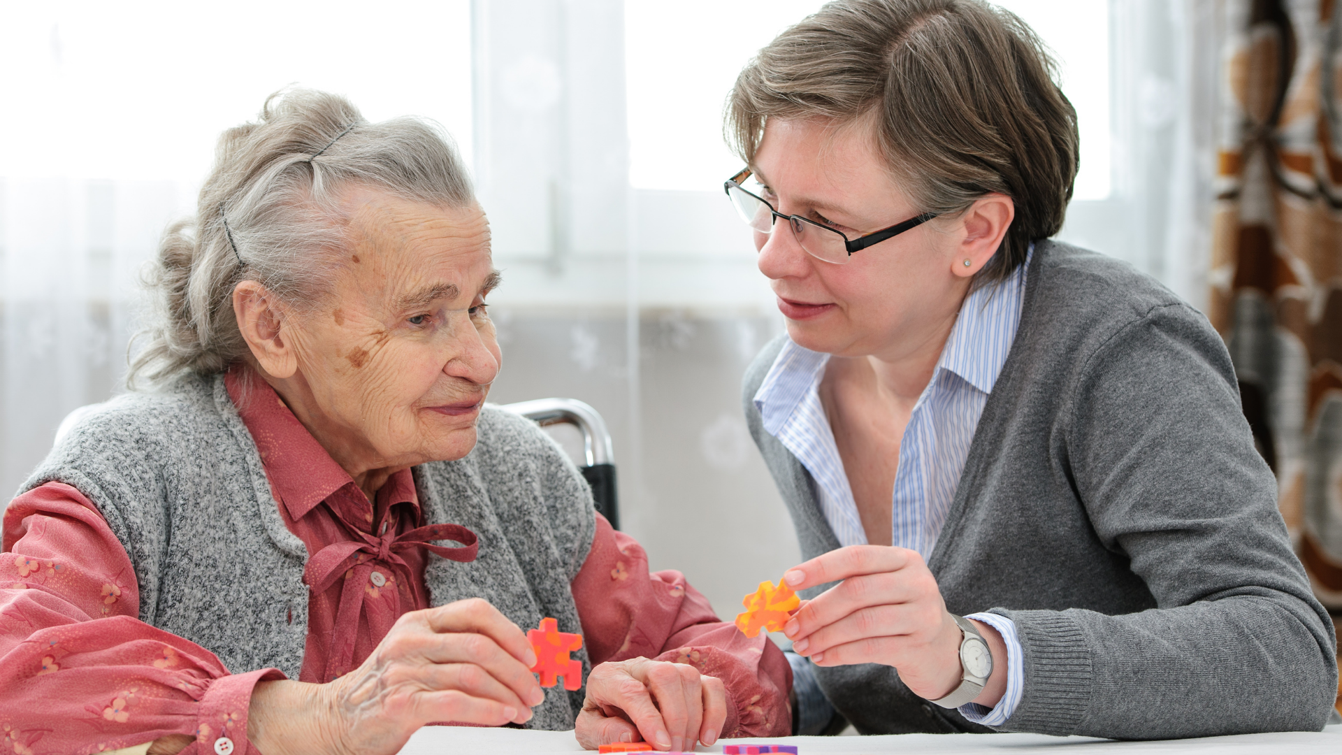 Two women talking and crafting together at a table in a bright room