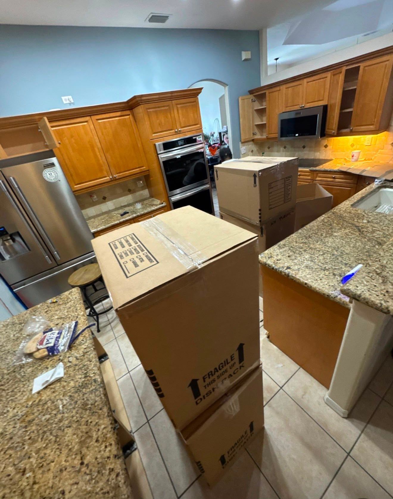 Boxes stacked in a kitchen with wood cabinets and granite countertops during a move