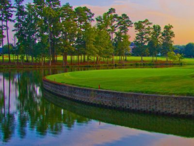 A golf course with a lake and trees in the background