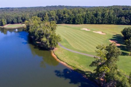 An aerial view of a golf course surrounded by trees and a lake.