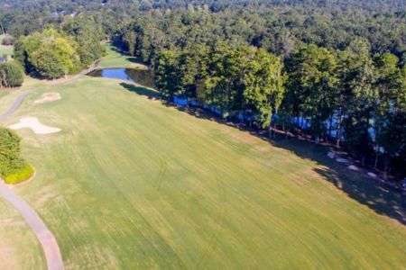 An aerial view of a golf course surrounded by trees and water.