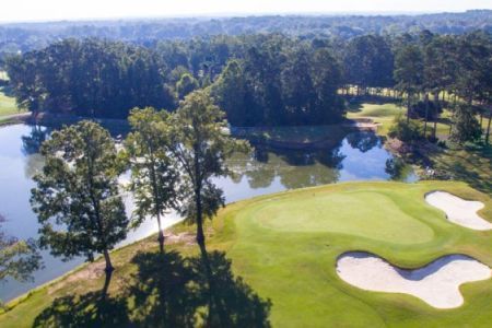 An aerial view of a golf course with a lake in the background.