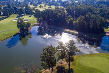 An aerial view of a golf course with a lake and trees surrounding it.