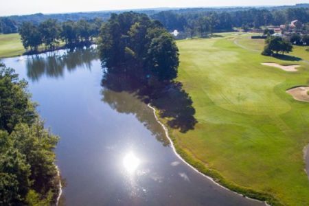An aerial view of a golf course surrounded by trees and a lake.