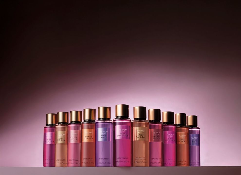 Hilera de frascos de cosméticos rosas y dorados sobre un fondo degradado rosa suave.