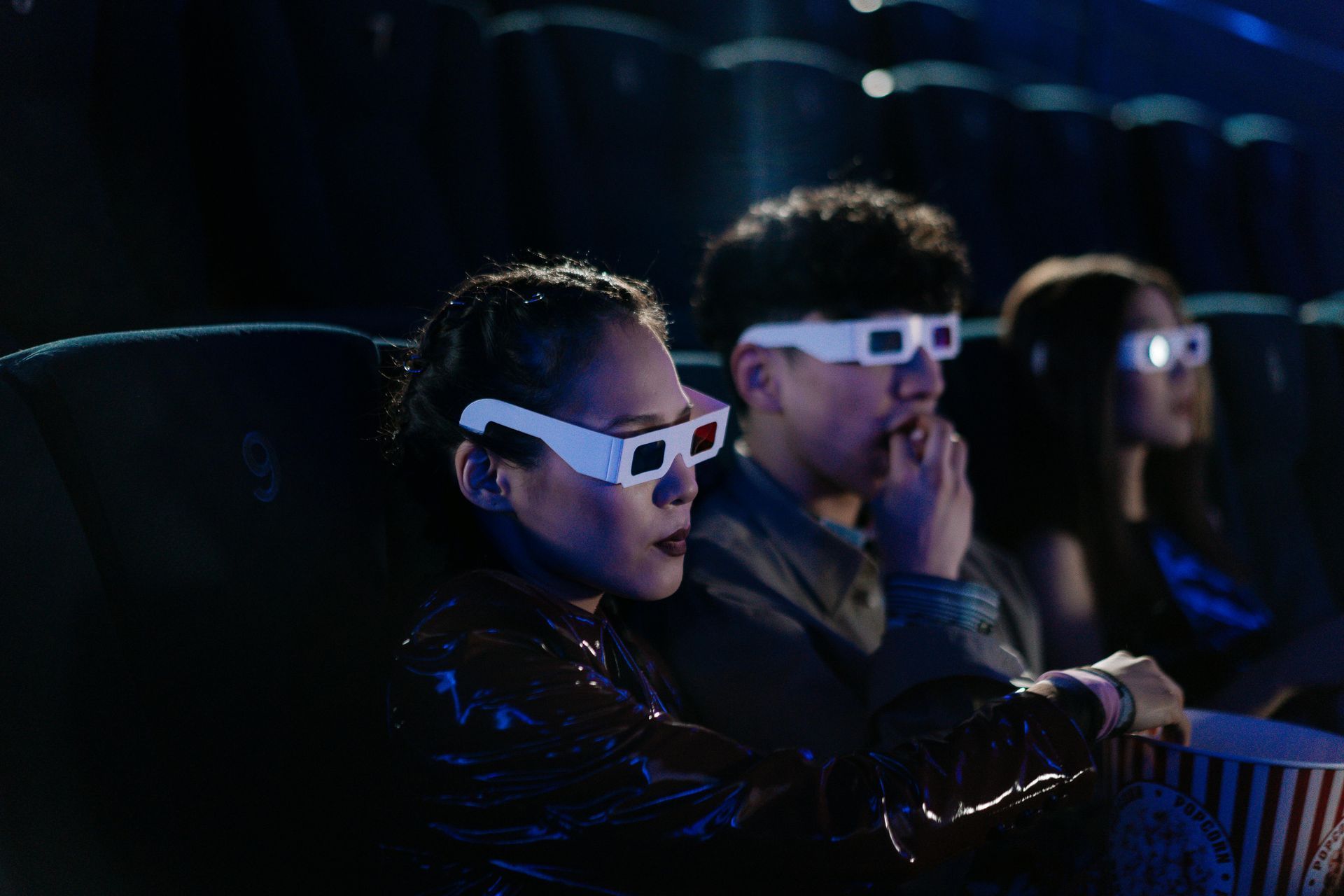 Personas con gafas 3D viendo una película en un cine oscuro.