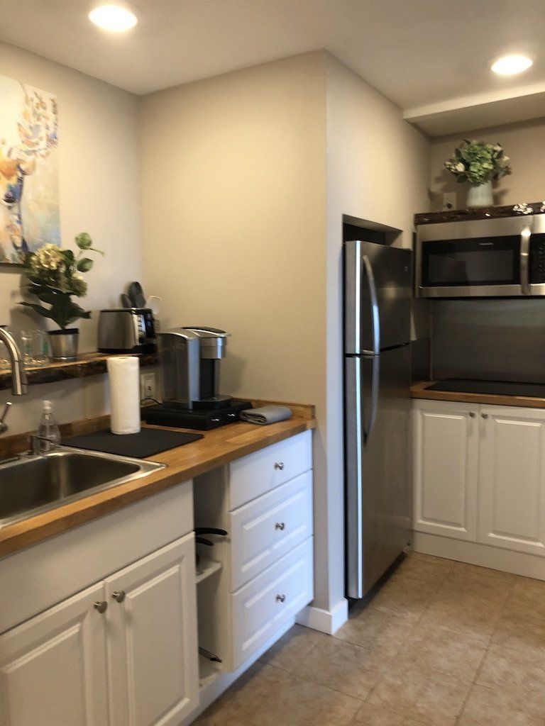 A clean, modern kitchen with white cabinets, wood countertops, stainless steel appliances, and a small sink.
