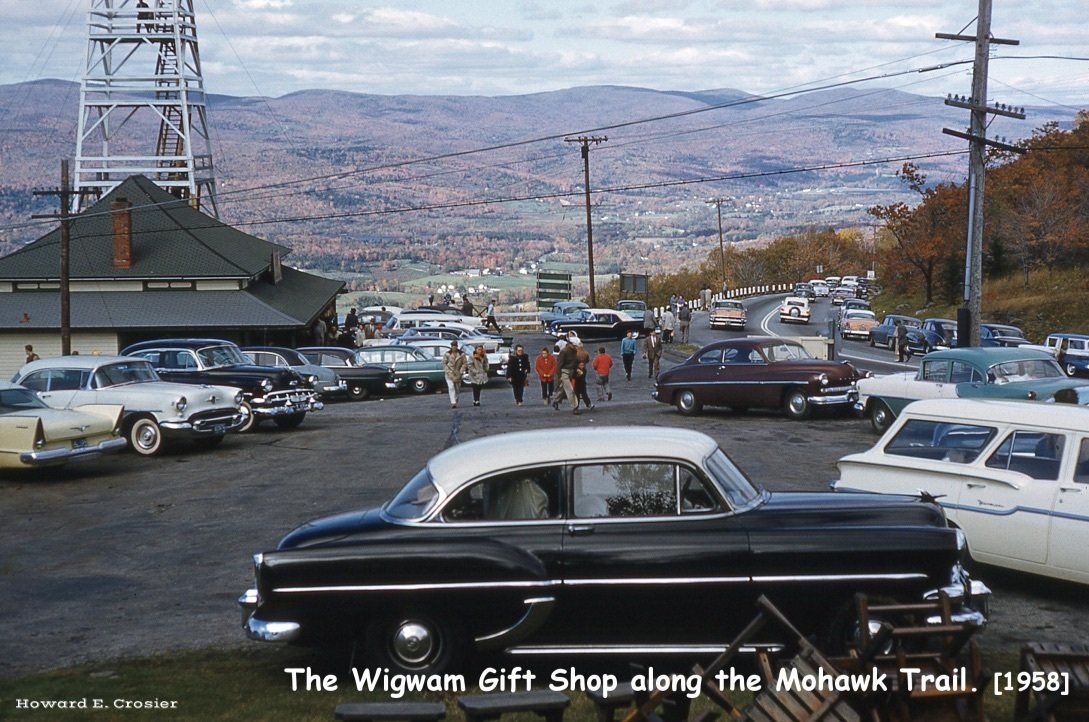 A 1958 scene of The Wigwam gift shop and a crowded parking lot on the Mohawk Trail, featuring many vintage cars.