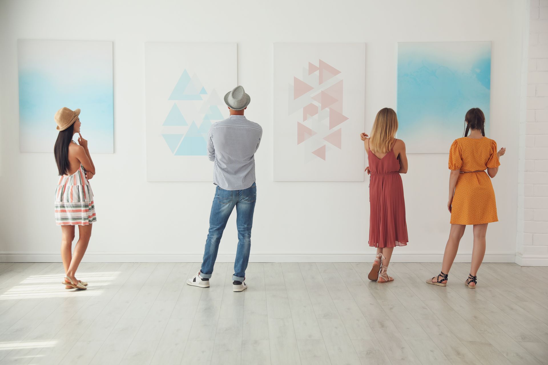 A group of people are looking at paintings in a museum.