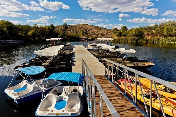 Boats and kayaks are docked at a dock on a lake.