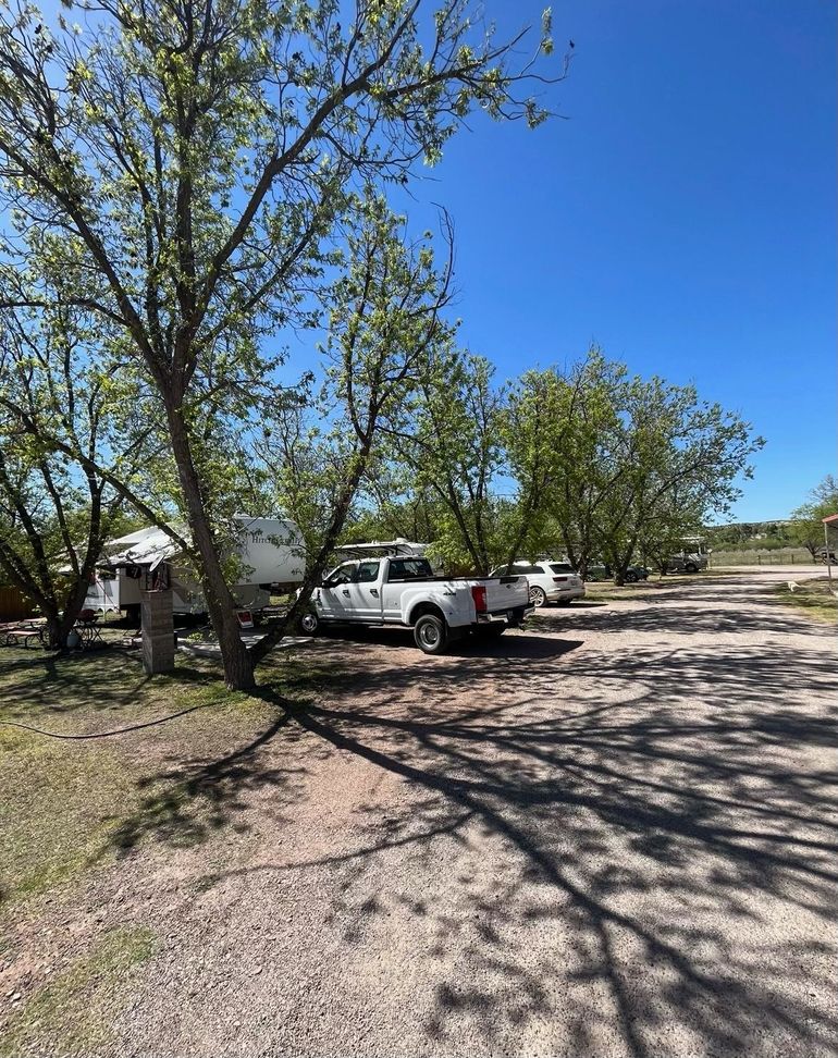 A white truck is parked in a parking lot next to a trailer.