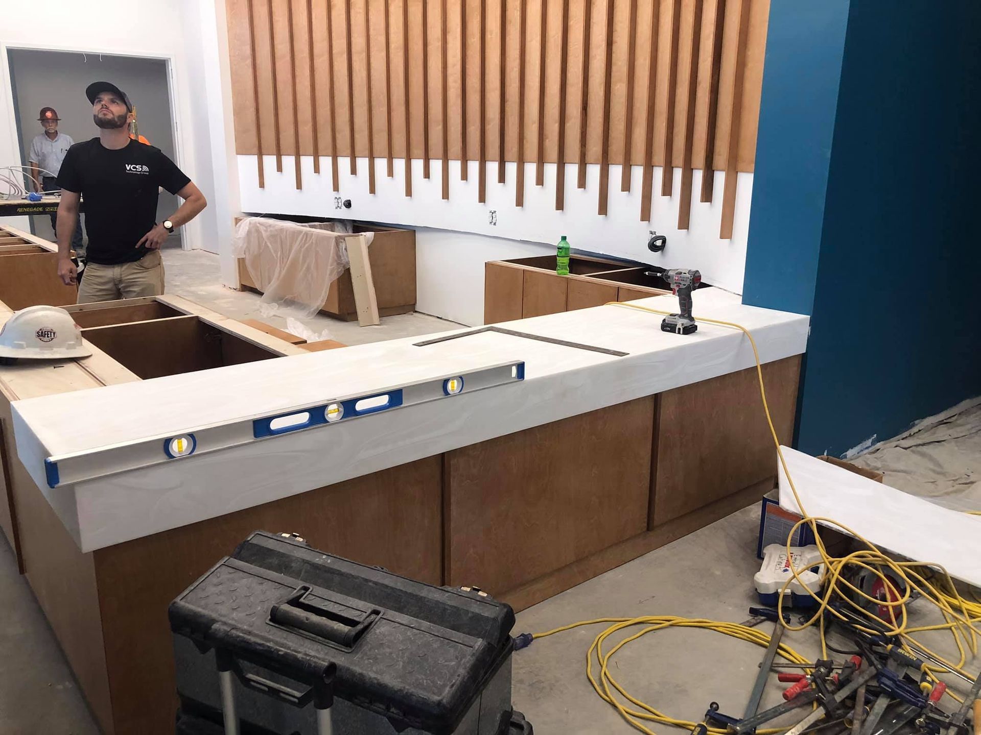 A man is standing at a counter in a kitchen under construction.