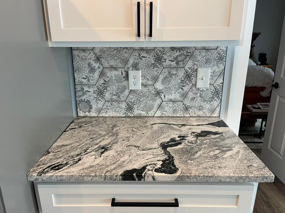 A kitchen counter with a granite counter top and white cabinets.