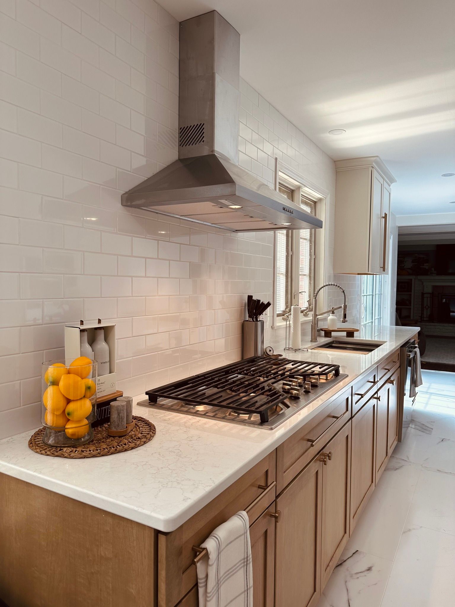 A kitchen with a stove , sink , and hood.