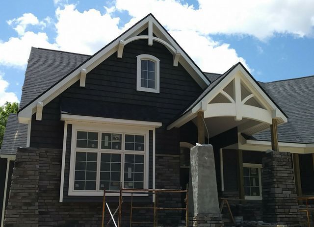 A black house with white trim and a gray roof