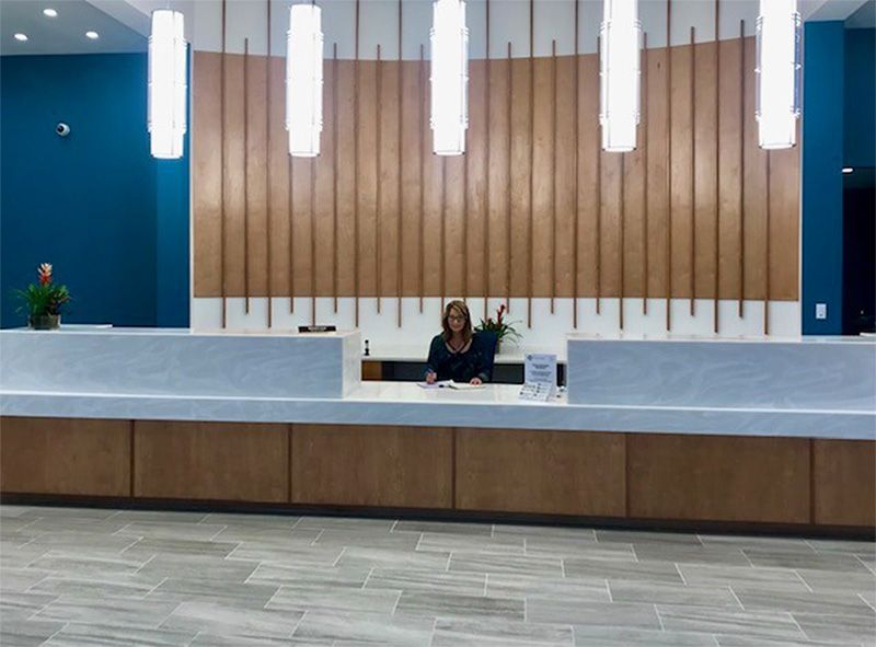 A woman is sitting at a reception desk in a hotel lobby.