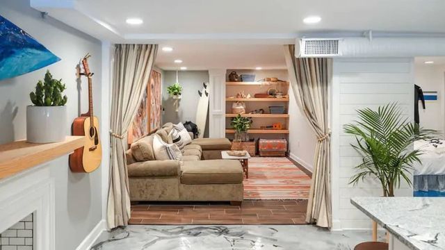 A living room with a couch and a guitar hanging on the wall.