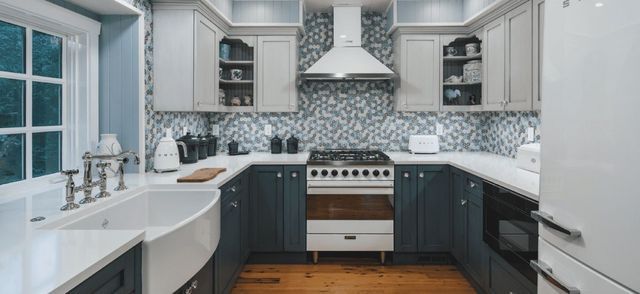 A kitchen with a stove , refrigerator , sink , and window.