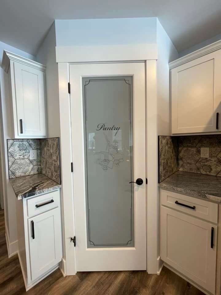 A kitchen with white cabinets and a pantry door.