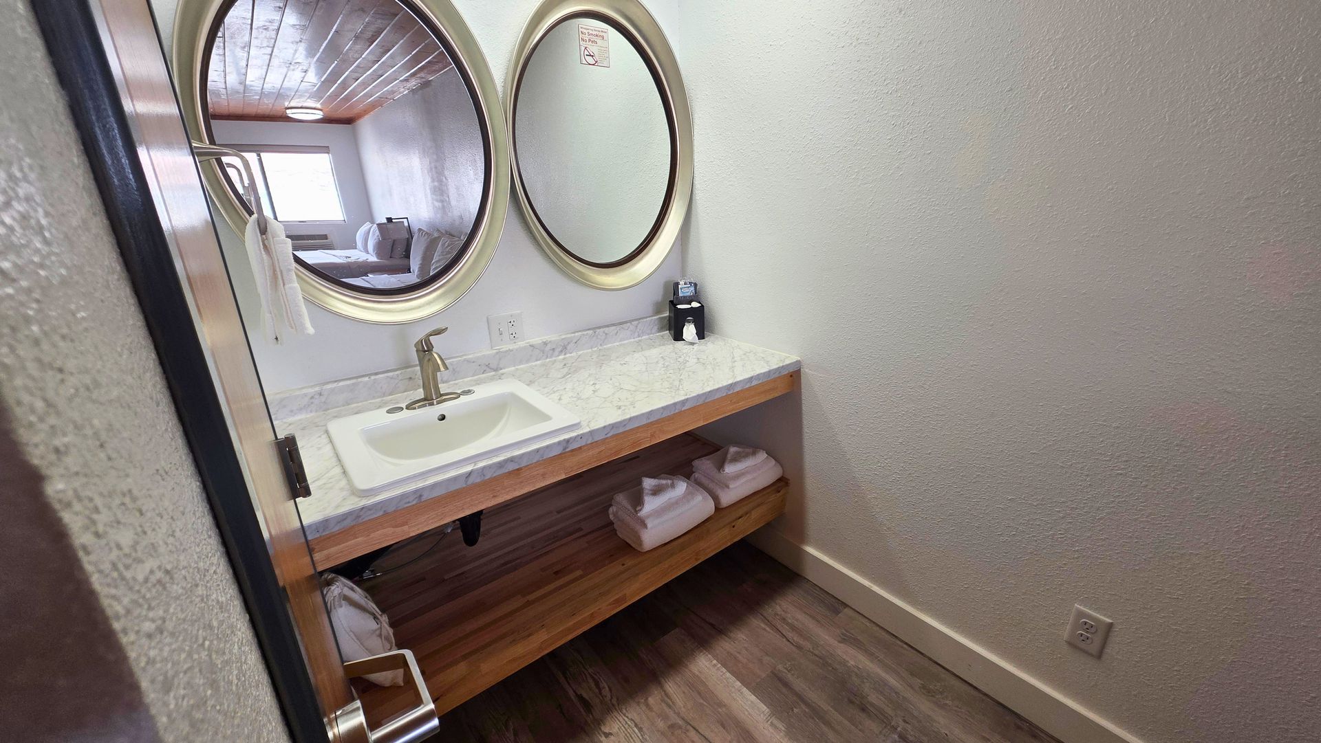Small bathroom vanity with oval mirror, white sink, and wooden counter under a slanted ceiling.