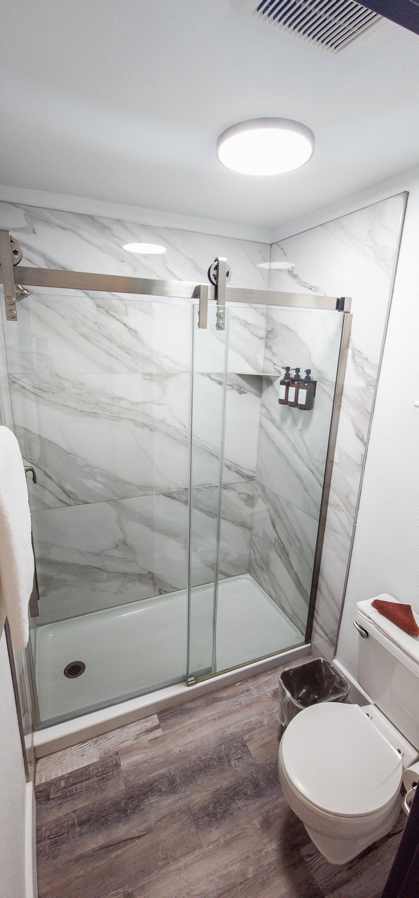 Small bathroom with glass shower, marble-look tile, and a white toilet.