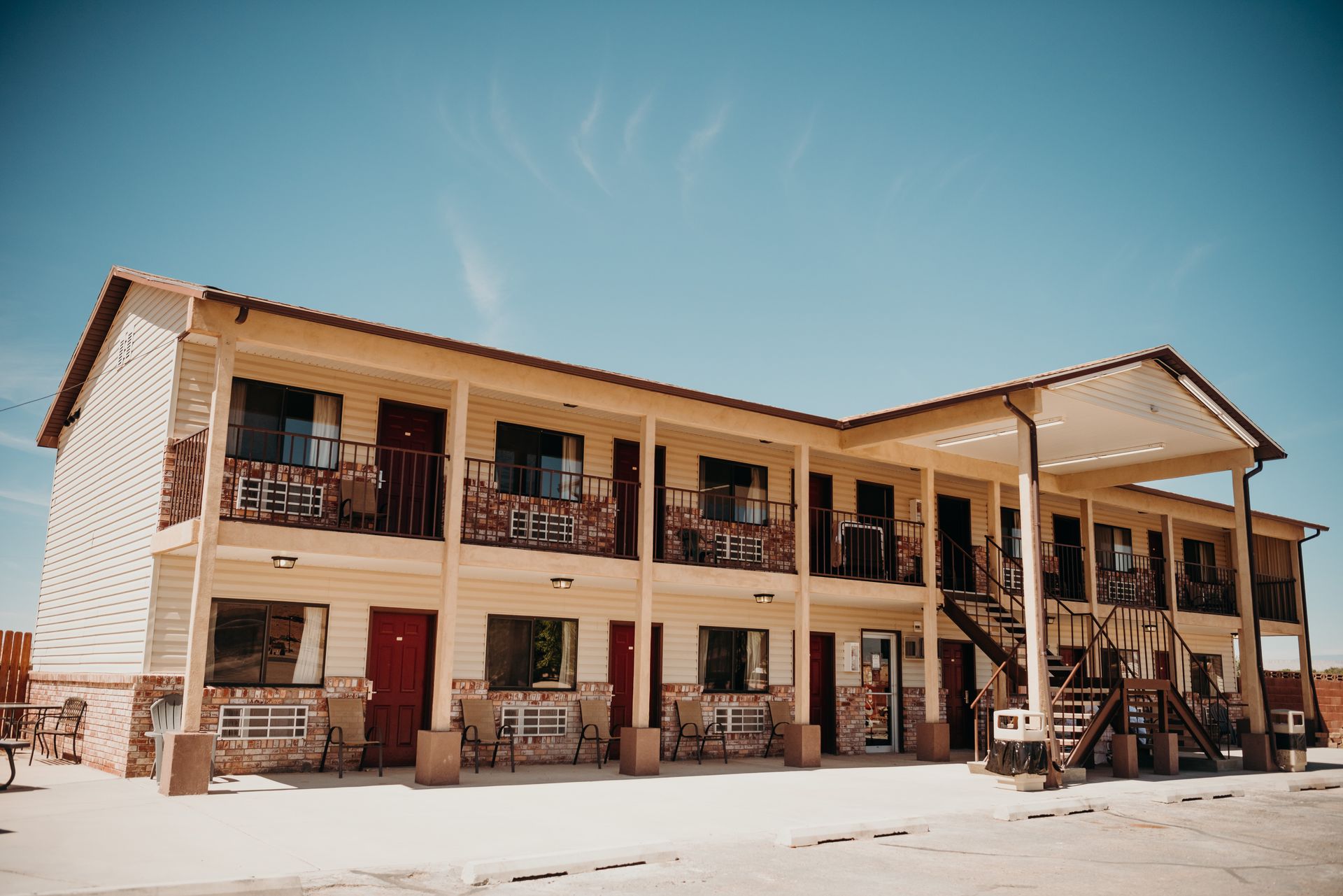 Two-story desert motel with balconies, wooden porches, and red doors under a clear blue sky