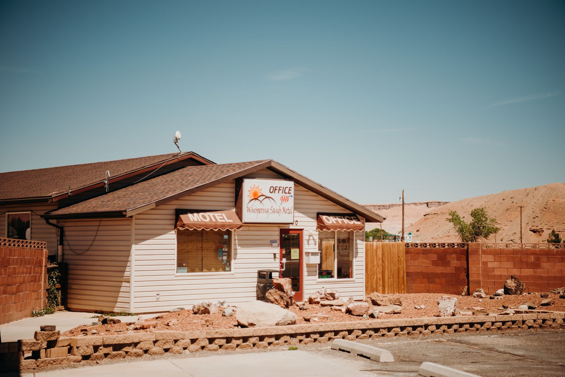 Small white building with a red roof in a desert landscape under a clear blue sky