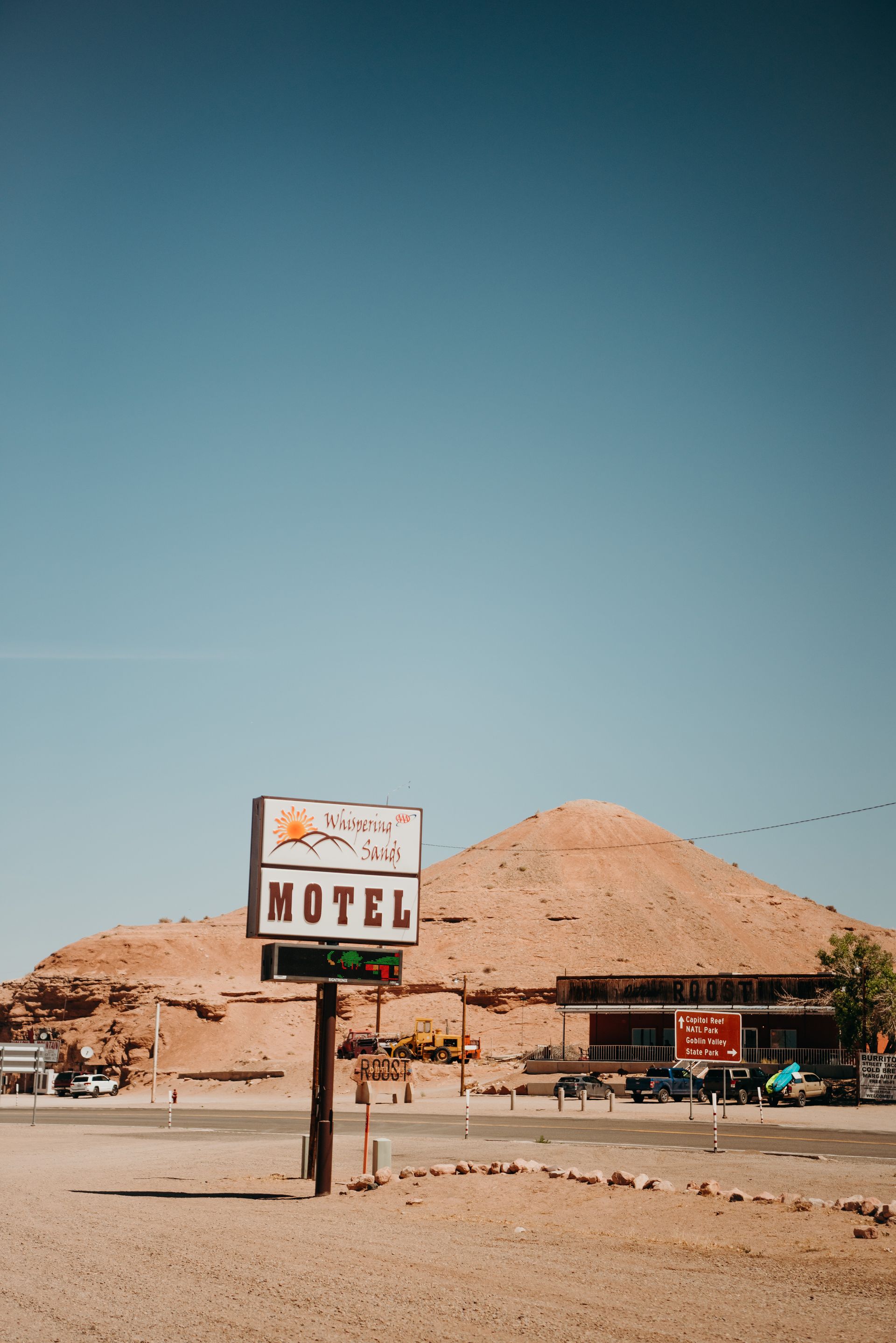 Desert roadside motel sign with rocky hills and a clear blue sky in the background