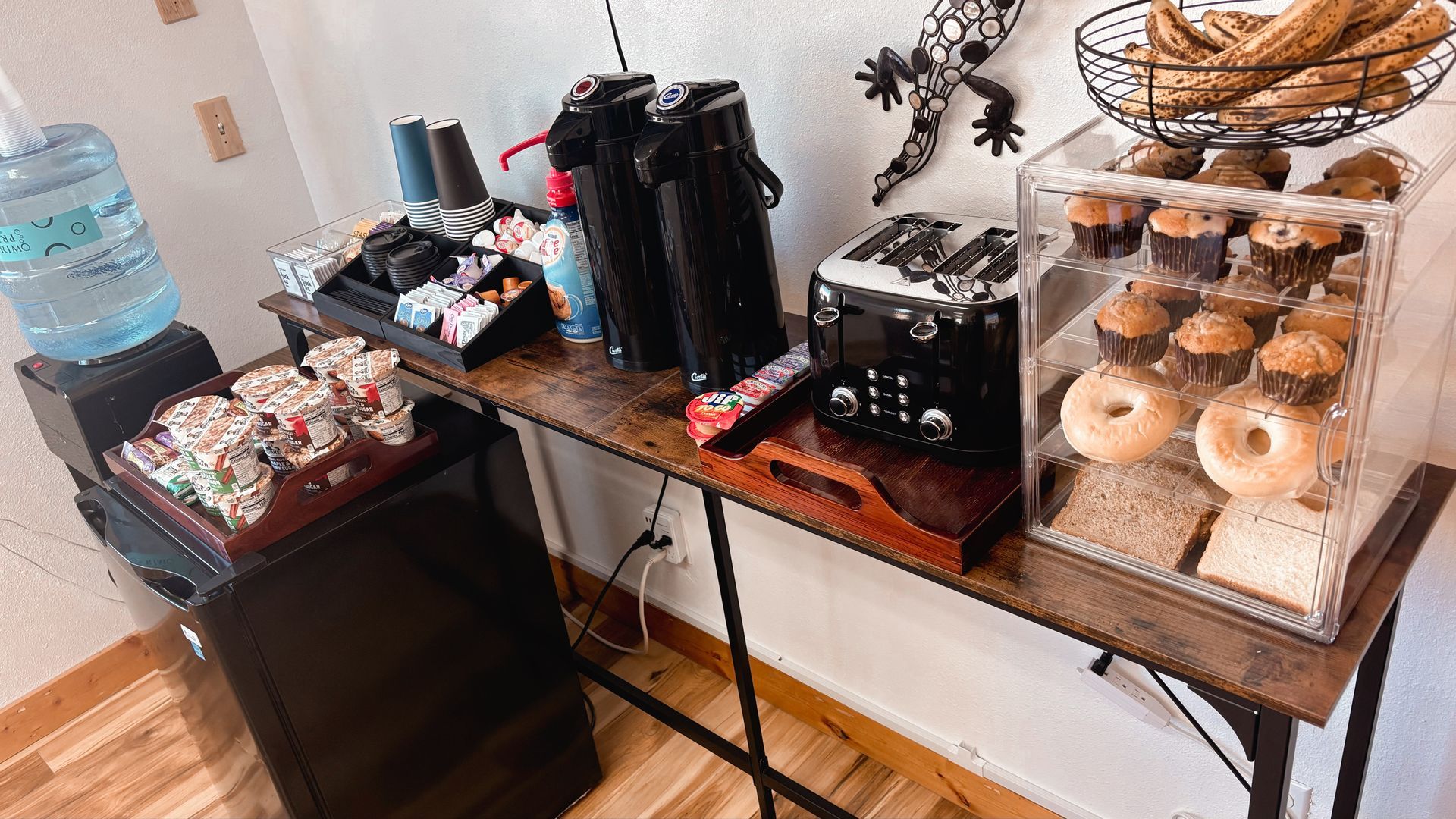 Coffee and pastry self-serve station with donuts, dispensers, and condiments on a black table