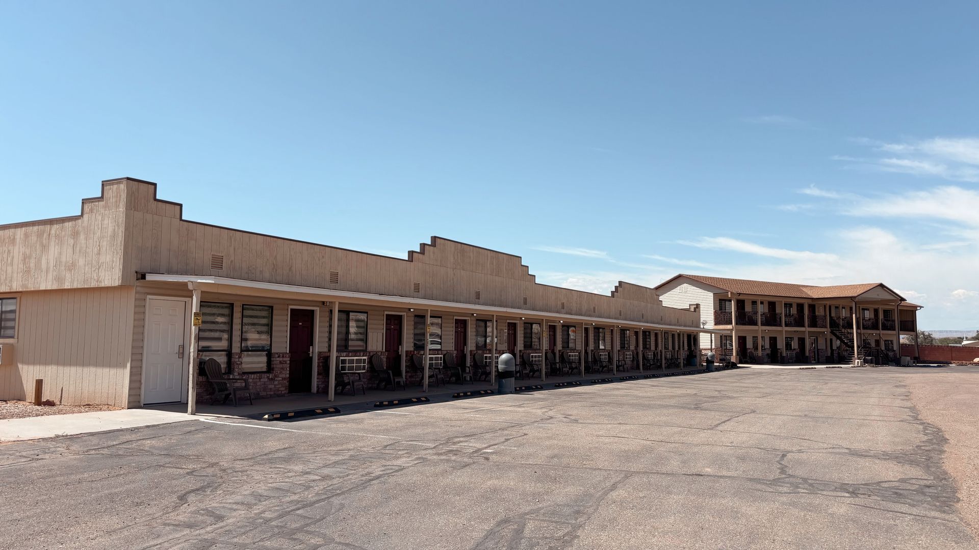 Deserted strip mall with tan stucco storefronts under a clear blue sky and empty parking lot