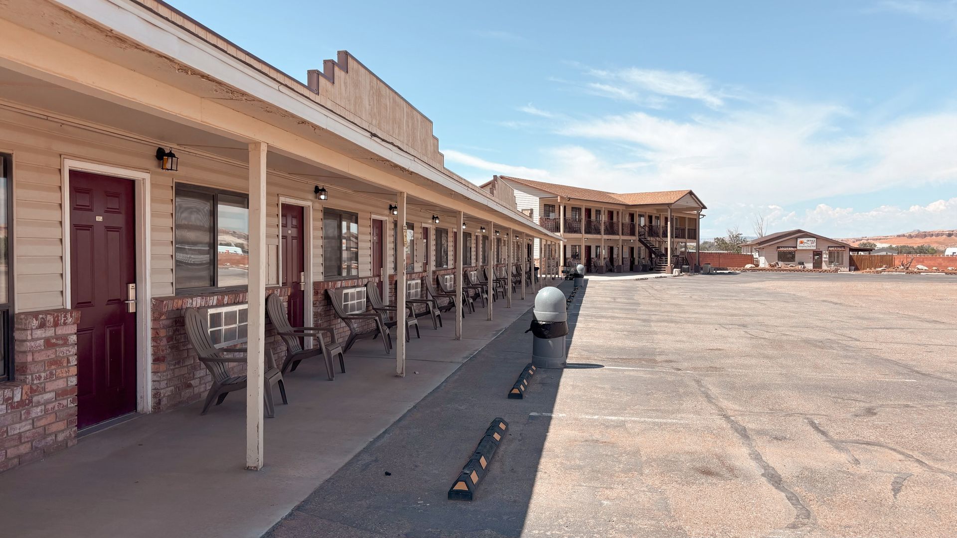 Covered outdoor walkway beside empty storefronts in a beige strip mall under a clear sky