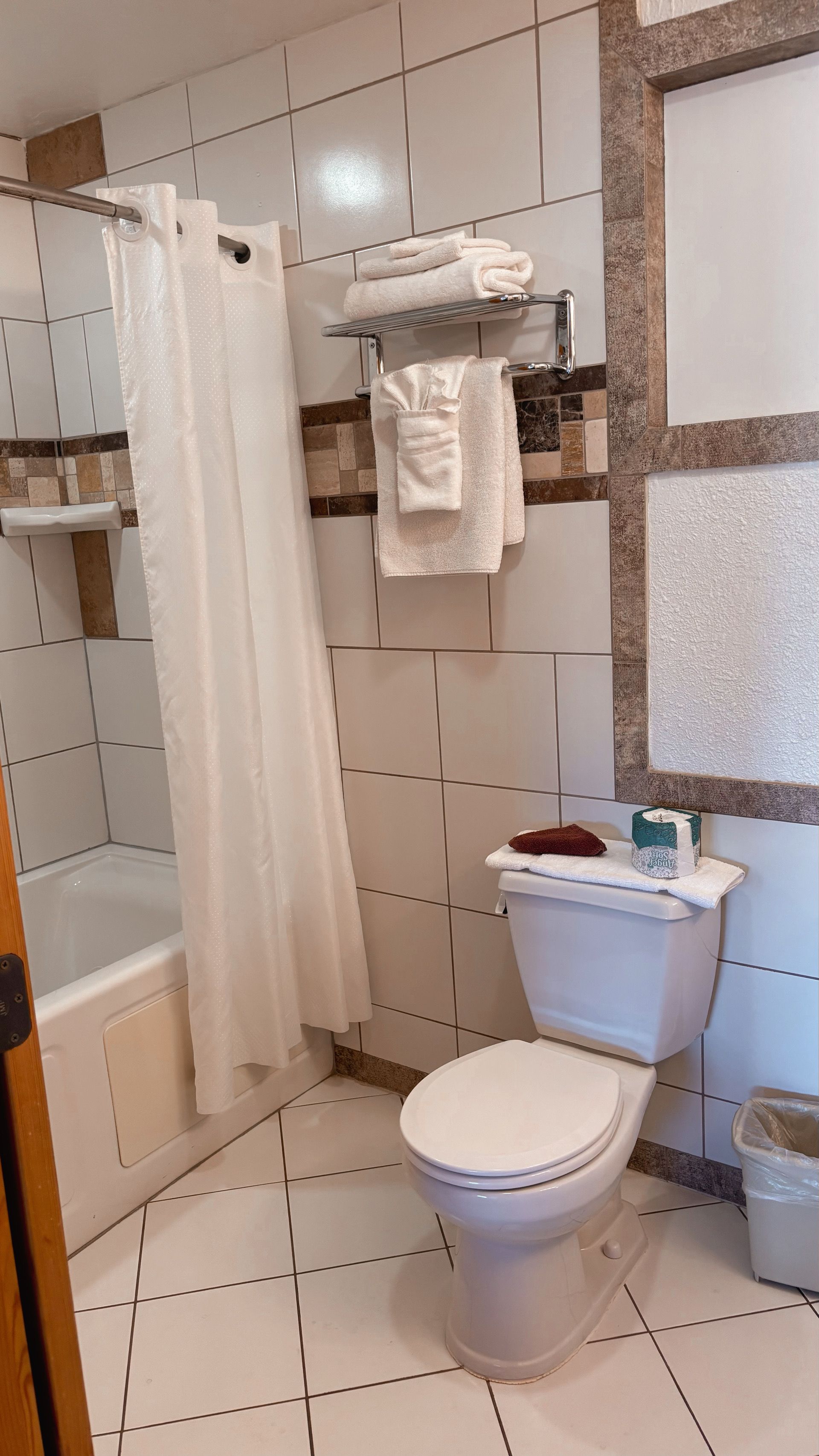Small bathroom with white tiled walls, toilet, shower curtain, and a sink partially visible.