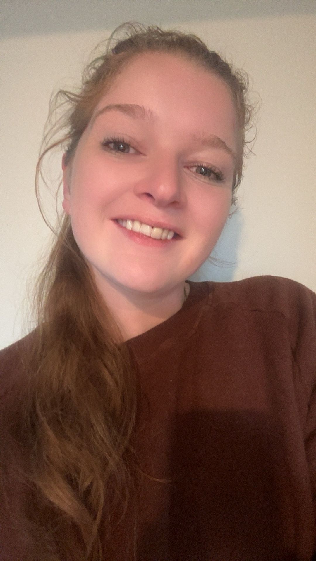 A woman in a brown sweater is smiling for the camera.